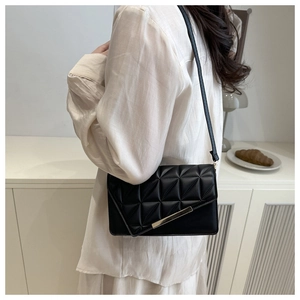 Detail of black quilted shoulder bag with triangular pattern and gold metal clasp