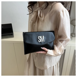 Detail of black faux leather envelope clutch with sparkling rhinestone SM logo ornament
