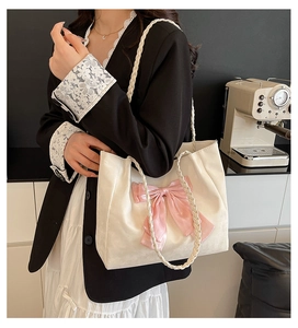 Detailed shot of white tote bag with pink satin bow and woven straps on model