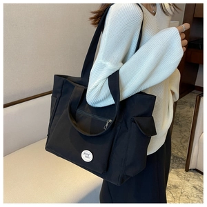 Detail of black Oxford tote bag featuring multi-pocket design and 'good luck' patch