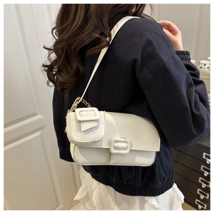 Close-up of a white leather shoulder bag with decorative buckles and small coin purse