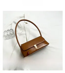 Detail shot of brown glossy baguette bag featuring a gold metallic buckle closure