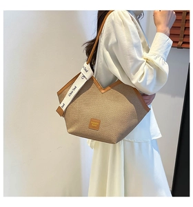 Detail of khaki tote bag featuring brown leather trim and decorative printed silk scarf