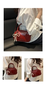 Detail of red glossy PU leather handbag with a pearl bow charm and logo printing