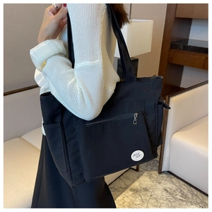 Detail view of large black oxford tote bag with exterior zipper pocket and side pouch