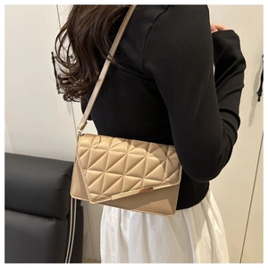 Detail of beige quilted leather crossbody bag featuring geometric stitching and gold trim