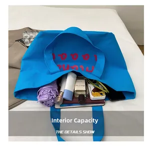 Detail showing high-capacity interior of blue canvas tote bag with various accessories