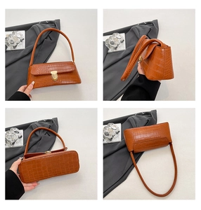 Detail view of brown crocodile texture shoulder bag with golden metallic clasp