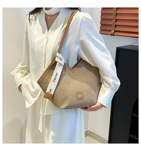 Close-up of khaki canvas tote bag with brown leather trim and stylish logo patch