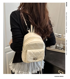 Rear view of cream quilted mini backpack with silver twist lock and chain straps on model