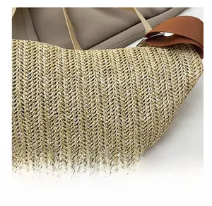 Detail showing the natural woven texture and brown strap of the crescent straw chest bag