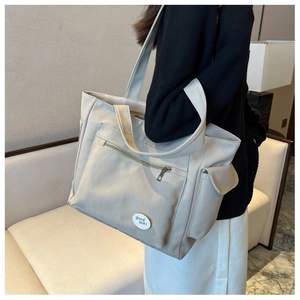 Detail view of large beige oxford tote bag with side snap pockets and a front zipper pocket