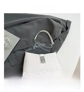 Detail of white woven texture shoulder bag with large silver square buckle and chain strap