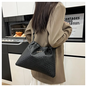Dettaglio borsa a tracolla intrecciata nera con texture fitte e finiture in logo dorato