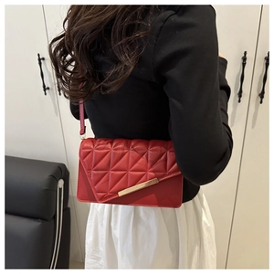 Detail of red quilted crossbody bag with geometric stitching and golden metal buckle