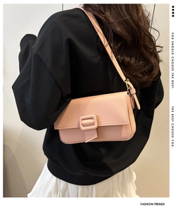 Pink lychee leather baguette bag with decorative buckle shown on a model's shoulder