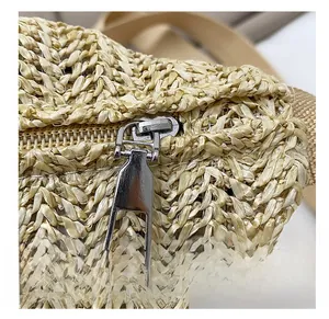 Close-up of a smooth silver metal zipper on a woven straw crossbody bag detail