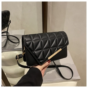 Detailed view of black quilted crossbody bag with gold metal clasp and geometric texture