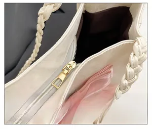 Detail of smooth gold dual zippers and pink silk bow on a cream woven tote bag
