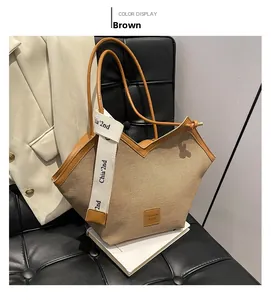 Detail of canvas tote bag with brown leather trim and fashion strap on leather chair