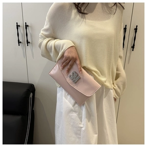 Close-up of pink envelope clutch bag featuring rhinestone studded SM metal logo detail