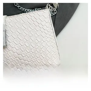 Close-up of white woven shoulder bag with silver metal buckle and chain strap