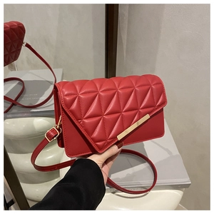 Detail of red quilted square bag with triangular stitching and gold metal trim