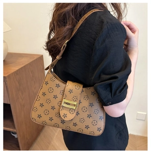 Detail of vintage brown shoulder bag featuring retro star pattern and gold metal buckle