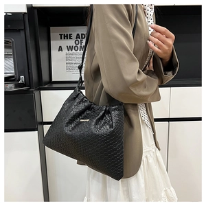 Dettaglio della borsa a tracolla intrecciata nera con pieghe e logo in metallo oro
