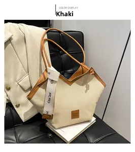 Detail of khaki canvas tote with brown leather trim and decorative branded straps