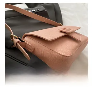 Close-up of pink litchi grain leather shoulder bag with adjustable strap and gold hardware