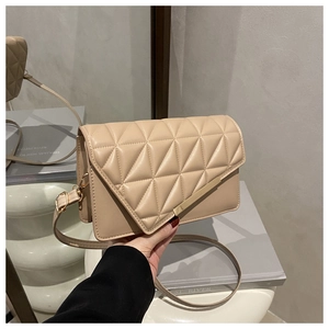 Detail showing beige quilted crossbody bag with asymmetric flap and gold metal bar