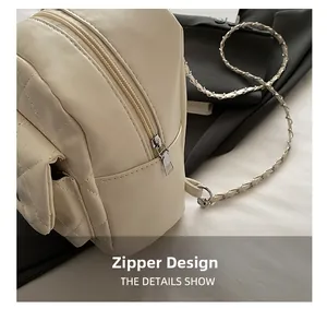 Detail shot of a quilted cream backpack featuring a metal zipper and woven chain strap