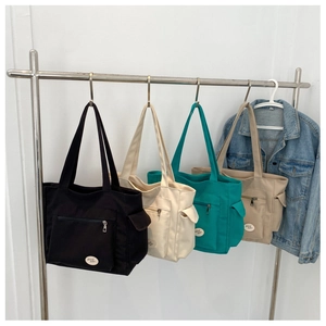 Hanging canvas tote bags in black, beige, teal, and khaki with outer zipper pockets