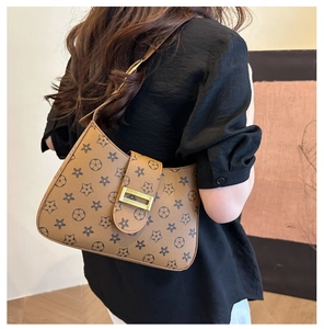 Detail of a brown shoulder bag featuring star patterns and golden metal buckle