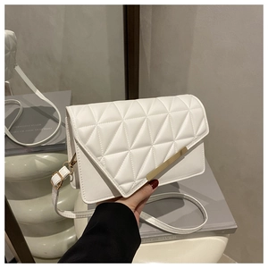 Detail of white quilted crossbody bag with gold metal trim and adjustable strap