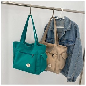 Detail view of large Oxford cloth tote bags in green and beige with multi-pocket design