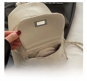 Detail showing the quilted front pocket of the beige backpack with a cosmetic mirror
