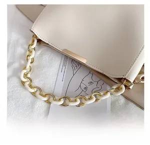 Close-up of cream bucket bag with white resin chain and golden metal hardware details
