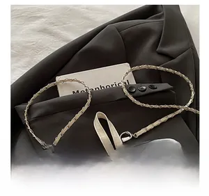Detail of white quilted leather backpack with woven chain strap on grey blazer