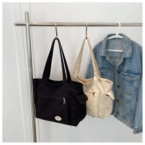 Detail view of Oxford cloth tote bags with front zipper pockets in black and cream colors