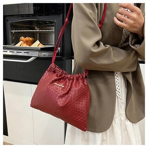 Dettaglio borsa a secchiello intrecciata bordeaux con coulisse e logo in metallo