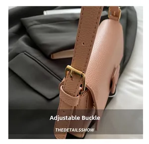 Detailed close-up of adjustable golden buckle and lychee grain leather strap on pink bag