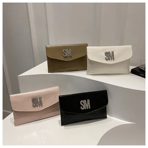 Close-up of four glossy envelope clutch bags in khaki, white, pink and black with metal logo