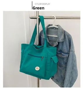 Detail view of teal green canvas tote bag featuring a stitched 'good luck!' circular patch
