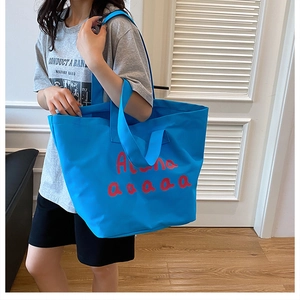 Detail of blue canvas tote bag with red Aloha script print and durable shoulder strap