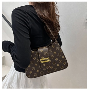 Detail of vintage brown monogram shoulder bag with gold clasp on a model shoulder