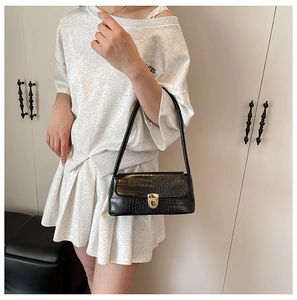Crocodile pattern black shoulder bag with gold buckle shown on a model