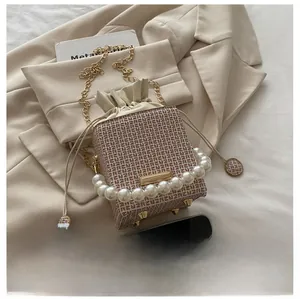 Detail of geometric mini bucket bag with pearl handle and cream drawstring pouch interior