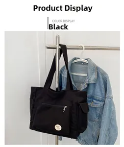 Detail of black oxford tote bag with zipper pocket and 'good luck!' patch hanging display